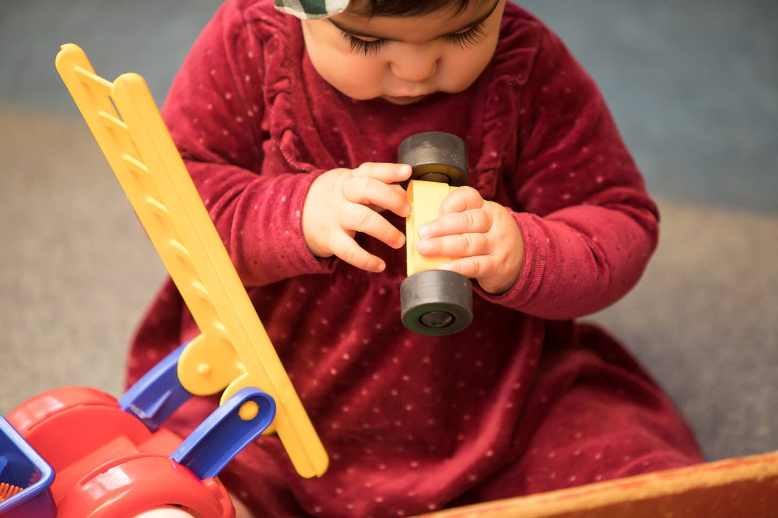 Ein Kind sitzt auf dem Boden und spielt mit Holzspielzeug.